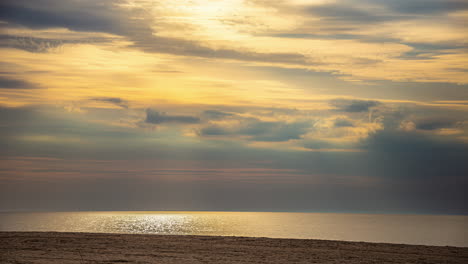 A-serene-beach-with-calm-waves-under-a-colorful-sky-during-sunset,-timelapse