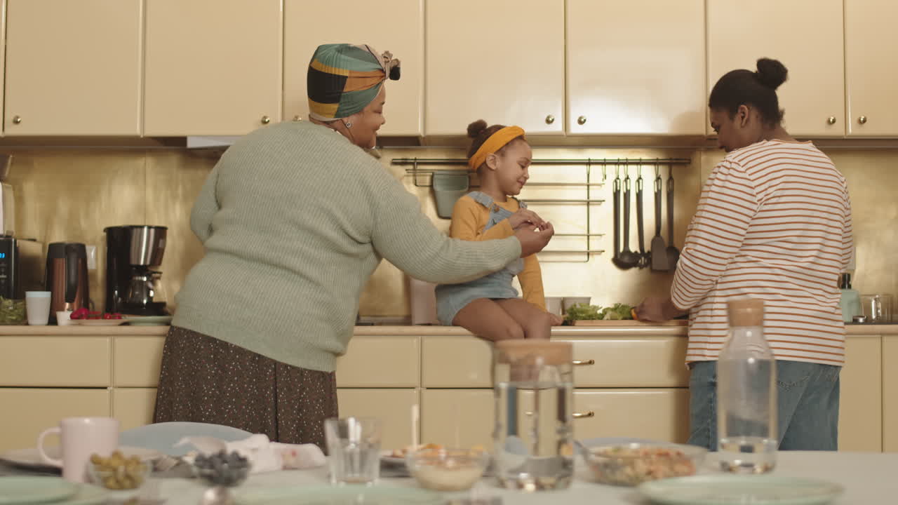 Little African Girl Watching Her Mom and Granny Cooking