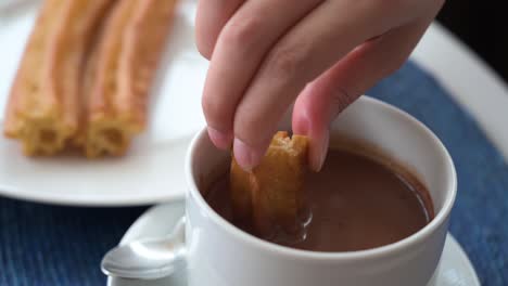 a slow-motion footage dipping spanish churros in hot chocolate sauce