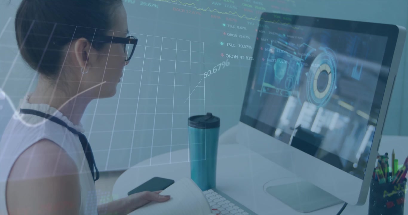 Animation of graph and trading board over asian woman watching video in desktop and writing in book