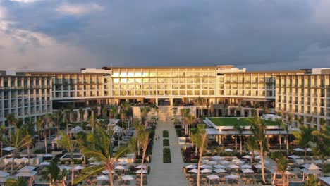 Tropical-resort-in-sunrise,-sunset,-hotel-with-pool-area,-palm-trees-and-bars-in-golden-light,-Caribbean-vacation-destination,-honeymoon-escape-in-Dominican-Republic,-aerial-view