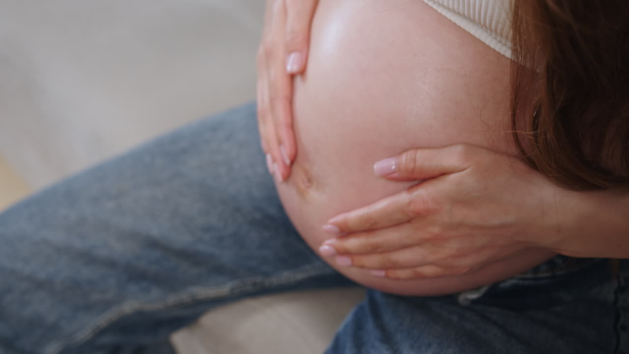 Le mani di una donna accarezzano teneramente il suo ventre gravido, simbolo di amore e attesa per la nuova vita
