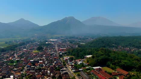 Grabag-village-in-valley-below-majestic-Java-volcanoes-silhouettes-aerial-view