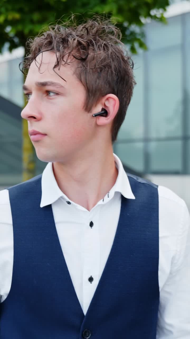 Young caucasian man listening to music or podcast with wireless earbud, enjoying audio content and modern technology for entertainment and communication. , slow motion, vertical shot