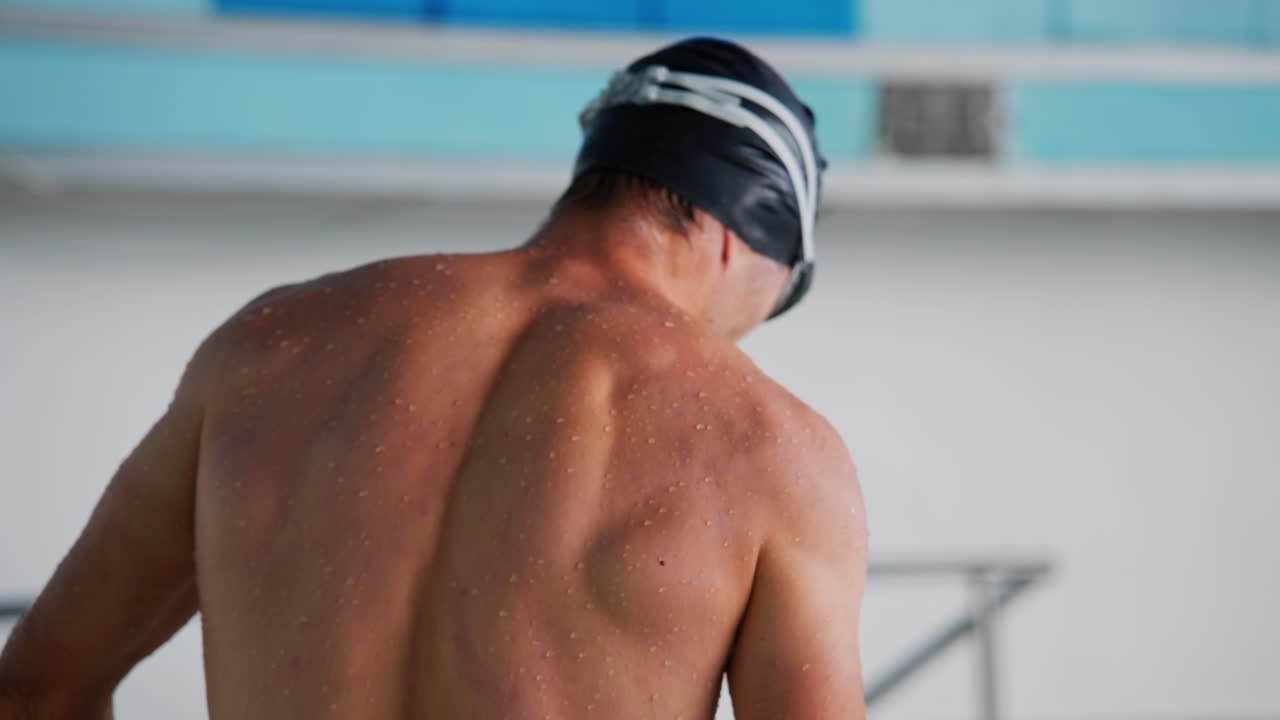 An Intense Moment Captured: A Swimmer Preparing for Dive with Concentration and Focus in an Indoor Pool Setting