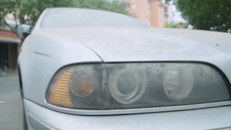 dirty headlight of silver car, close up detail wraparound right