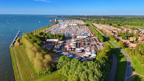 green waterfront of lake markermeer in lelystad, the netherlands. drone footage approaching the yacht club with lots of vehicles.