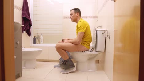 Man sitting on toilet finishing toilet paper roll and yelling