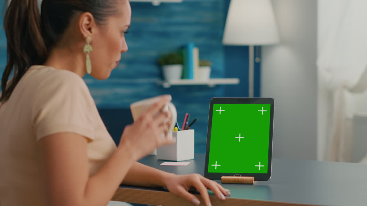 mujer freelancer sosteniendo una taza de café mirando una tableta