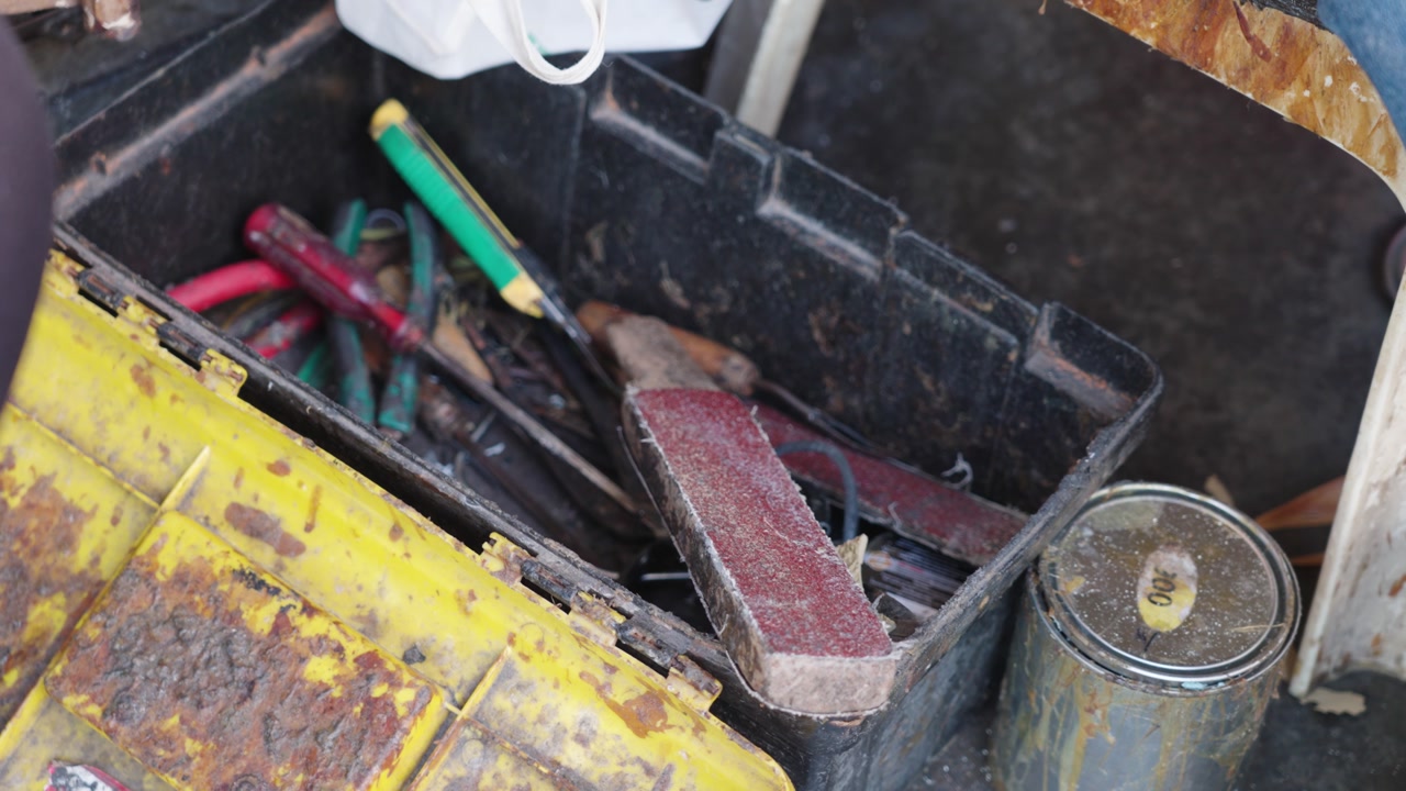 Detailed view of a cobbler’s toolbox with rasp and sanding tools in Malaysia. Authentic workspace scene highlighting manual labor, repair craft, and traditional skills.