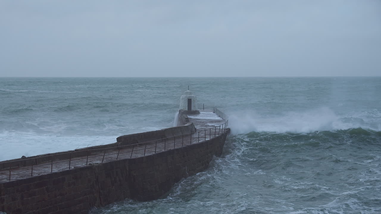 파도가 부서지면서 영국 portreath의 돌 부두 주변에서 바다가 부풀어 오릅니다.