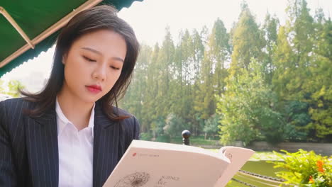 young businesswoman reading a book in a park