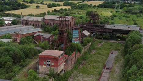 Verlassene-Alte-überwucherte-Kohlenmine-Industriemuseum-Gebäude-Luftbild-Ziehen-Sich-Langsam-Zurück