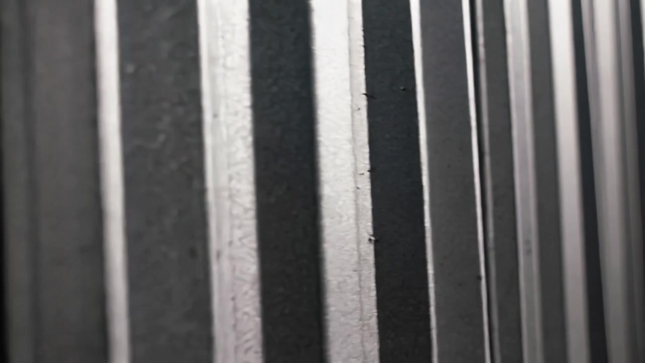 Telecamera in movimento che inquadra una parete di lamiera ondulata presso la porta di un magazzino, rivelando giunture e imperfezioni