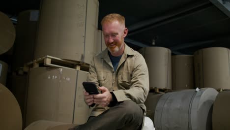 worker using smartphone in a paper warehouse