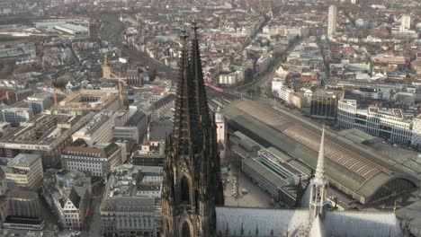 Aerial-descending-shot-of-tall-tower-of-gothic-Cologne-Cathedral.-Tilt-up-reveal-panoramic-view-of-large-city.-Cologne,-Germany