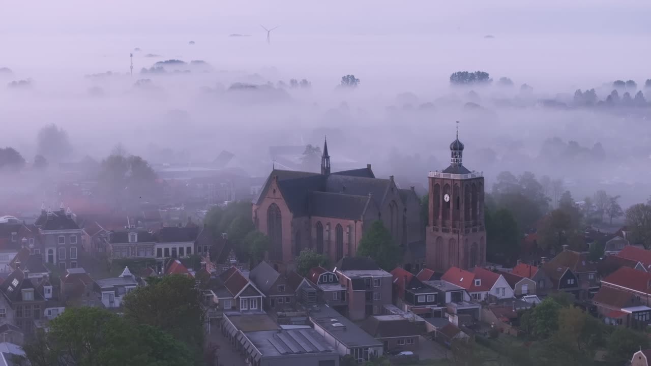 Workumer Kirche in nebliger Stadt bei Sonnenaufgang, Niederlande