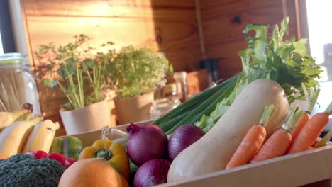 Crate-of-organic-vegetables-on-countertop-in-sunny-kitchen,-slow-motion