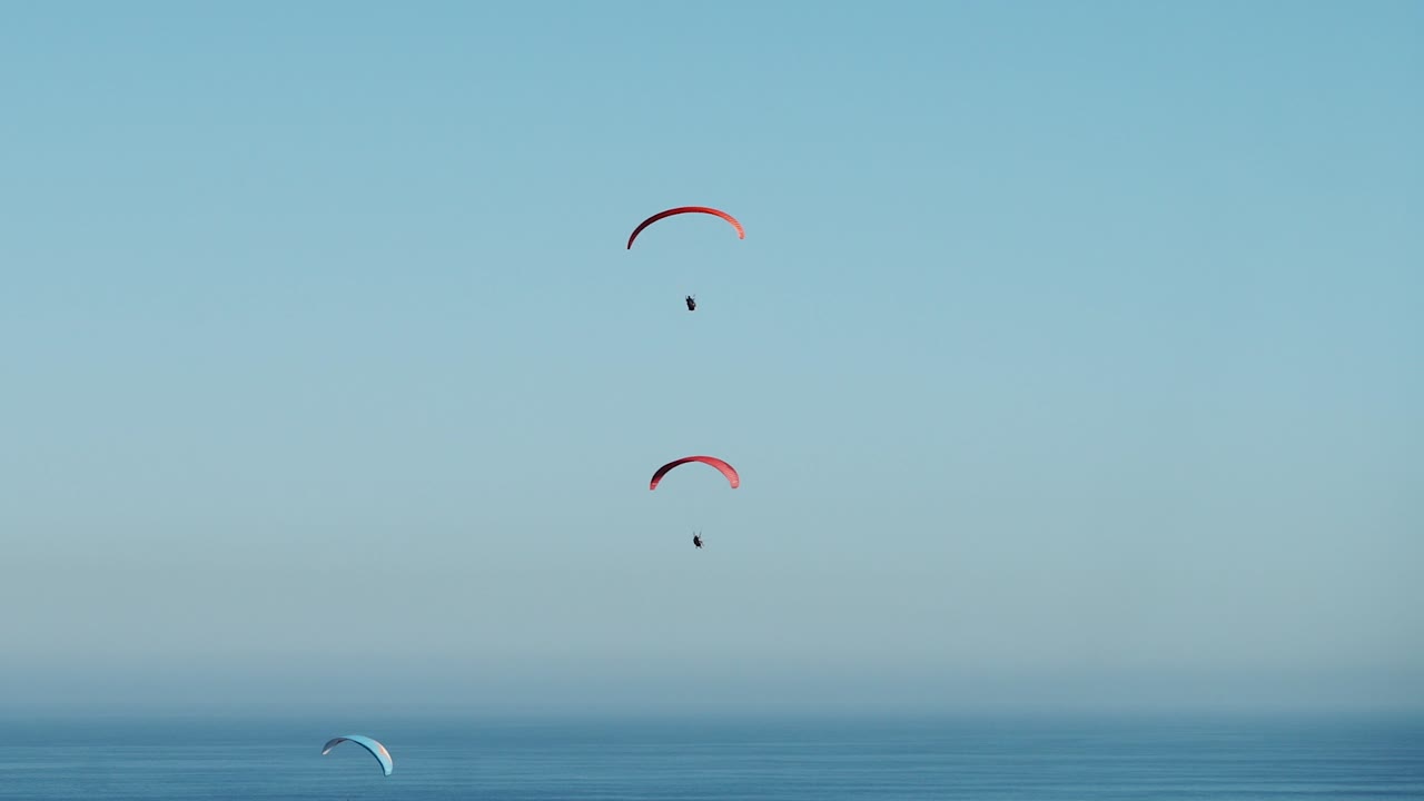 parapente volando en el cielo azul sobre el océano, mañana soleada