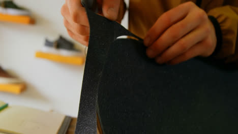 close-up of young man cutting skateboard grip tape in a workshop 4k