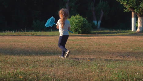 young-lady-walks-holding-blue-butterfly-net-in-hand