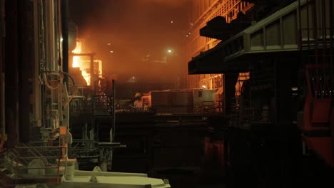 molten metal pouring in foundry at night, fiery glow illuminating industrial scene