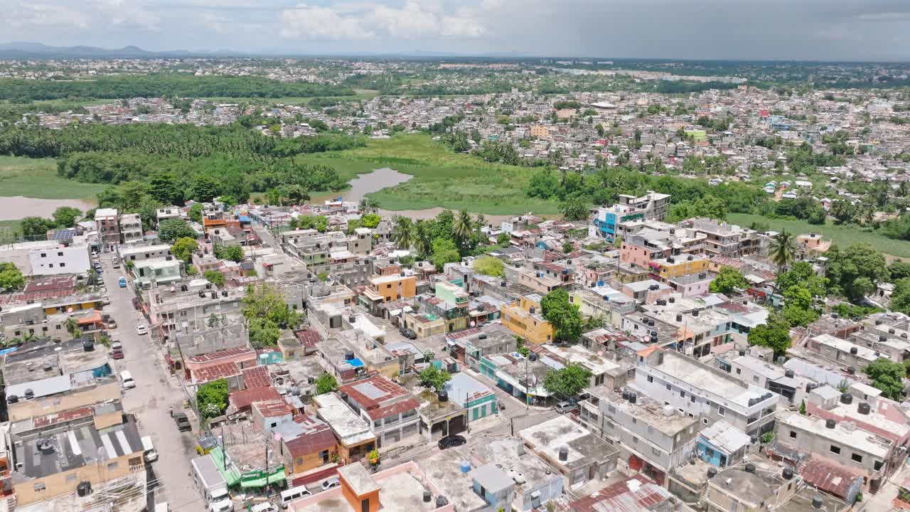 Aerial flyover BARRIO SIMON BOLIVAR District and Rio Ozama River in background during sunny day