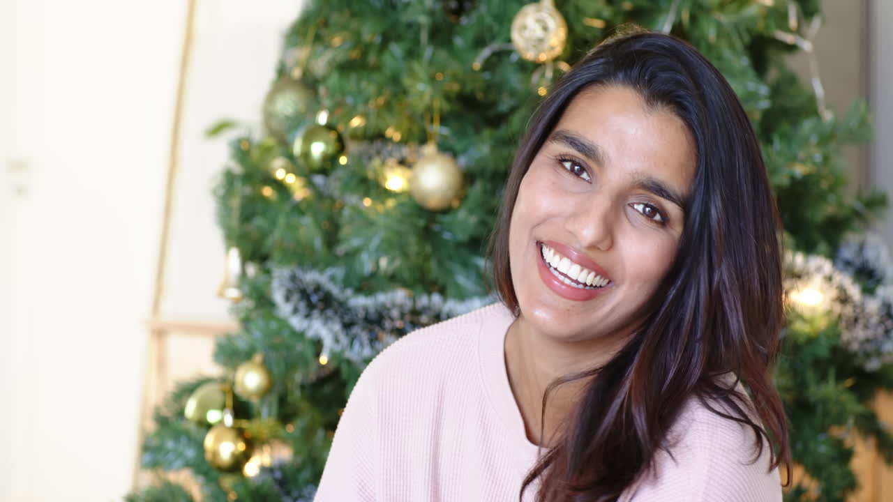 Smiling woman enjoying festive holiday moment by Christmas tree at home