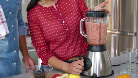 pareja preparando jugo de frutas en la cocina