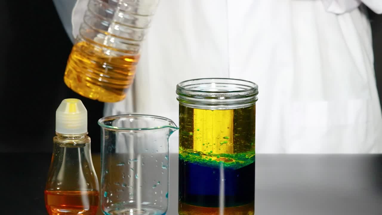 A person pours liquid into a jar, creating distinct colorful layers with visible separation.