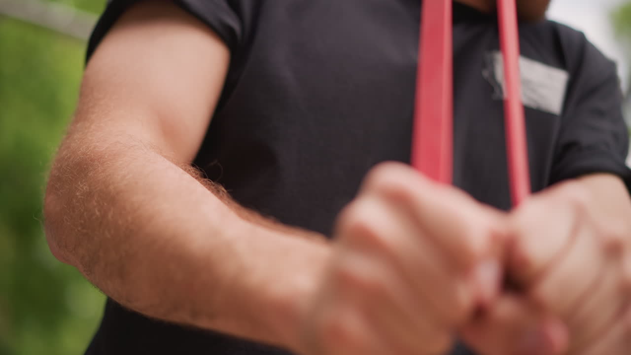 Closeup Of Man Stretching Resistance Band Outdoors Showing Muscle Engagement, Man Exercises Outdoors By Pulling Resistance Band Demonstrating Strength And Tension In Upper Body Muscles