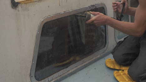 carpenter re-sealing windows of wooden boat with sika flex mastic waterproof sealant