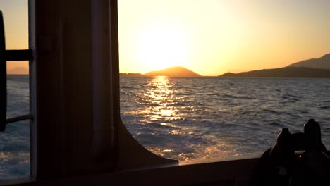 Vista-Desde-El-Interior-De-Un-Ferry-Navegando-Por-El-Mar-Jónico-Al-Atardecer,-Con-Olas-Espumosas