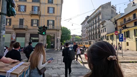 people crossing street near tram in milan