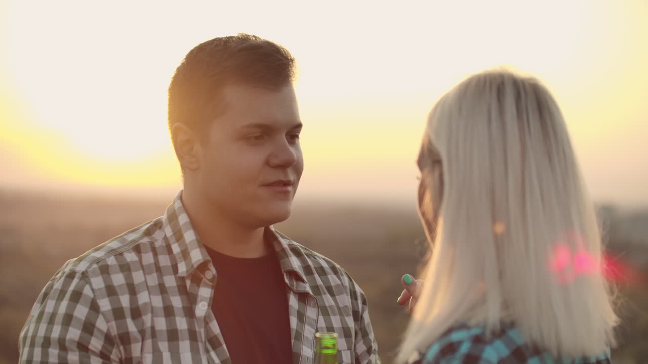 Loving couple in plaid shirts enjoy a moment with each other on a roof rail. The girl strokes his boyfriend the guy looks into the eyes of his girlfriend.