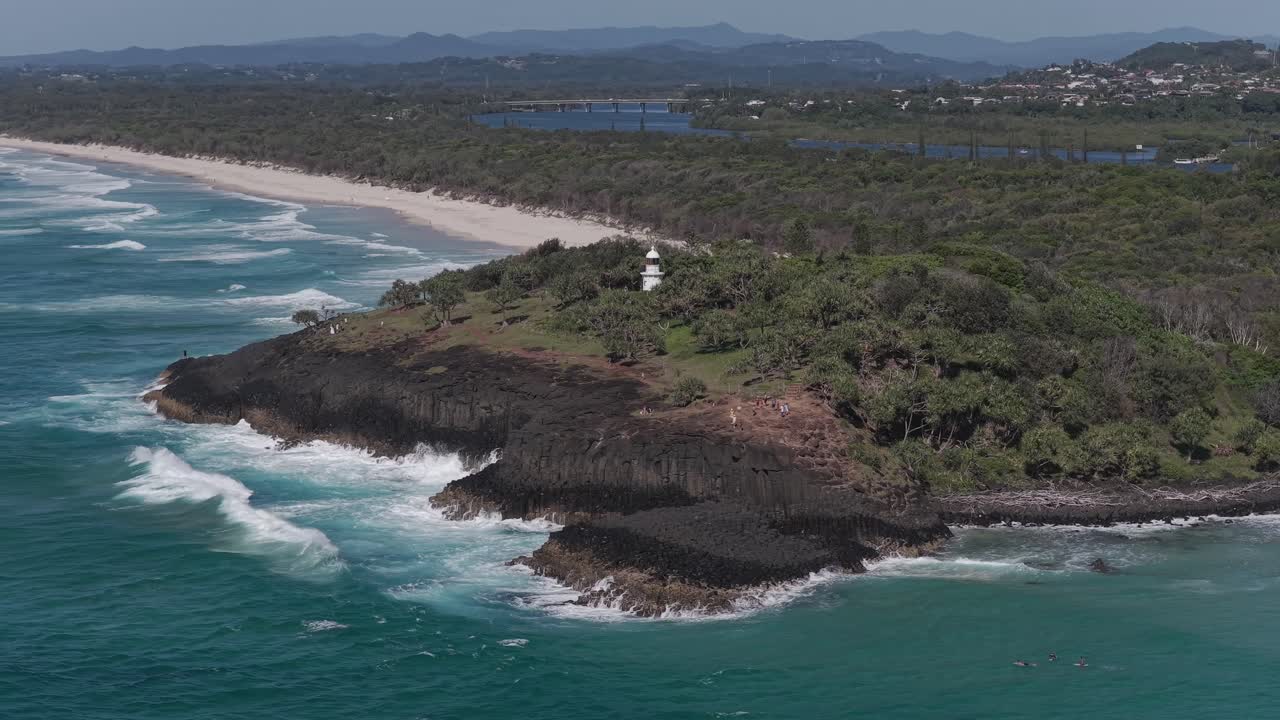 Faro di Fingal Head su un promontorio verde lussureggiante con il fiume Tweed sullo sfondo. NSW, Australia. Ripresa aerea orbitante