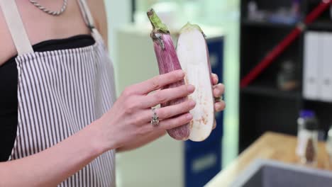 hands holding halves of a freshly cut eggplant