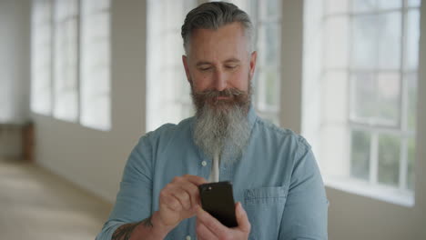 close up portrait of mature caucasian man texting browsing using smartphone mobile technology looking senior male stylish beard enjoying digital comunication