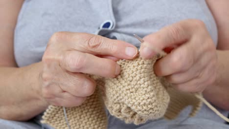 knitting with needles close-up. the pensioner is engaged in a well-deserved rest with his favorite hobby, needlework. old hands of grandmothers knit socks and scarves for the grandchildren