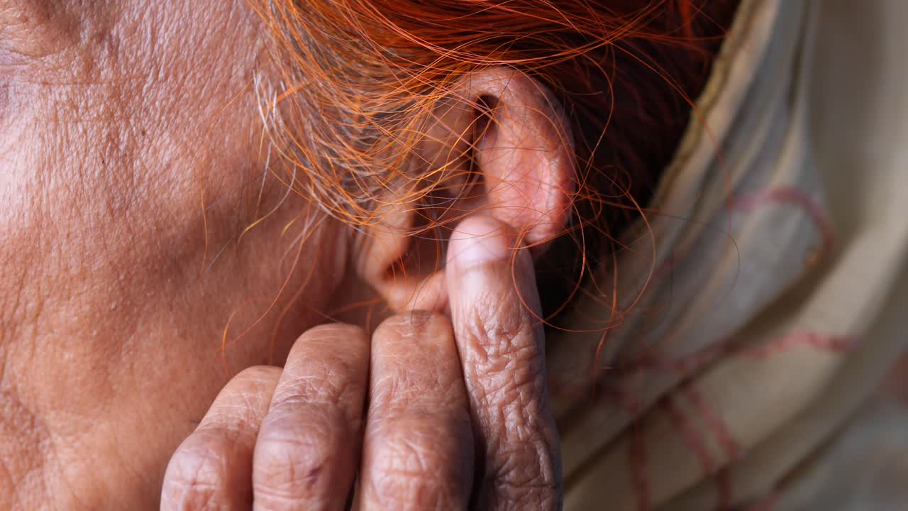 primer plano de la oreja y la mano de una anciana