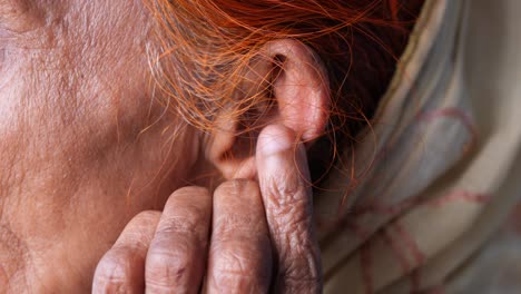 close-up of elderly woman's ear and hand