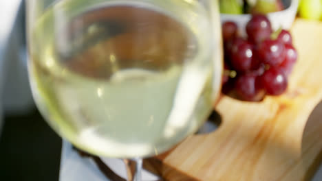 close-up of white wine glass and fruits on table