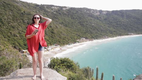 niña tomando selfie en la cima de la montaña praia brava en arraial do cabo, río de janeiro