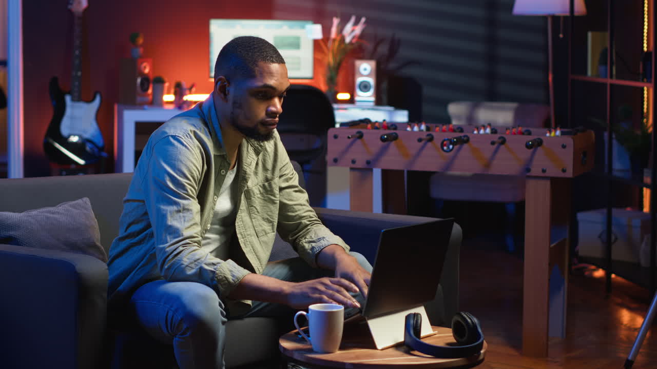 Vertical Video African American young adult working remotely on laptop under loft neon lights