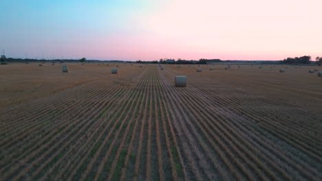 Flying-Above-the-Field-With-Hay-Rolls-Sunrise