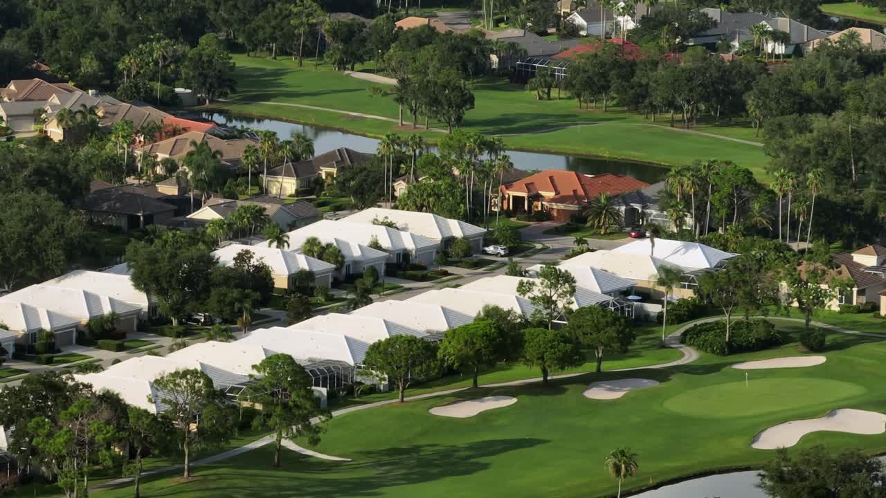 Luxury houses in golf club of Bradenton, Florida. Aerial wide shot. Sunset time with palm trees and golf course