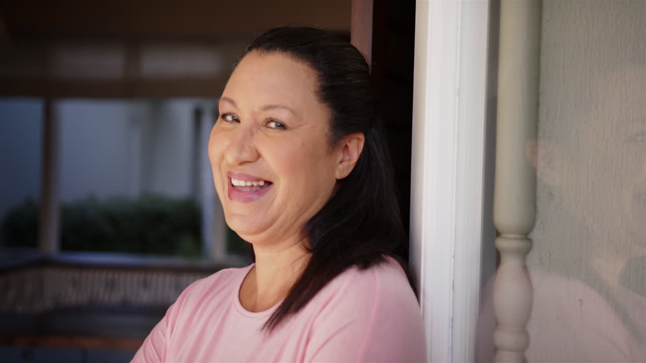 Smiling mature woman leaning against doorframe, enjoying relaxed moment at home
