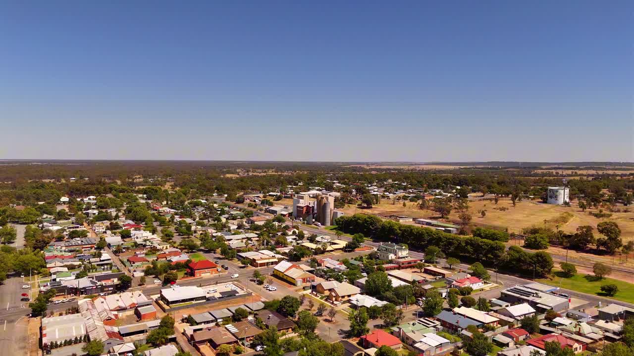 Il centro della città di Narrandera con tetti raggruppati, strade alberate e ampio orizzonte sotto la luce del giorno, ascesa aerea stabilita