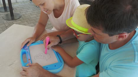 father drawing a picture on magnet board for son