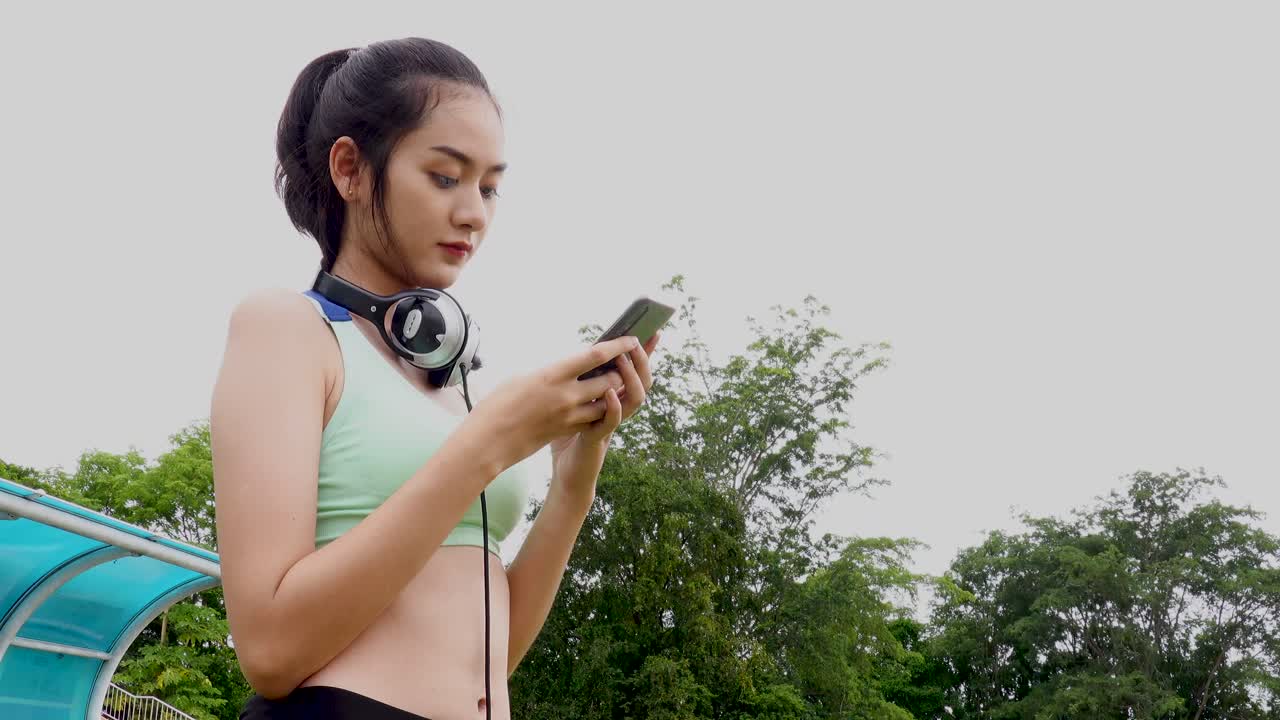 mujer deportiva feliz con auriculares, está buscando música en línea usando su tableta digital después de hacer ejercicio en el estadio, el deporte y el concepto de actividades de ocio